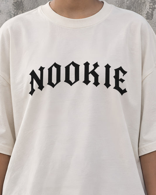 Close do logo NOOKIE em letra gótica preta, com 28 cm de largura, no peito da camiseta off-white