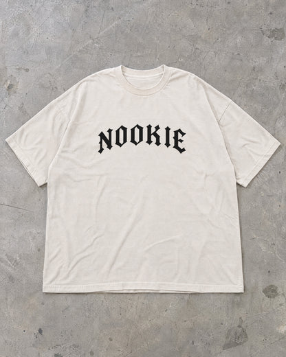 Camiseta oversized off-white Nookie Manchete estendida no chão de concreto, frente com o logo NOOKIE no peito