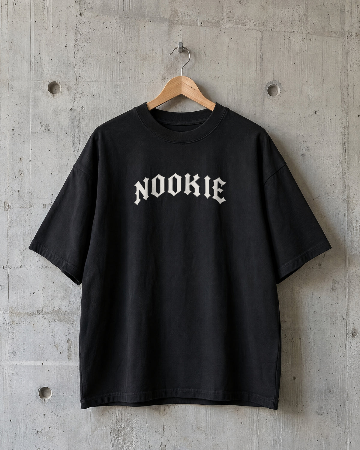 Camiseta oversized preta Nookie Manchete no cabide, de frente, com o logo NOOKIE em branco osso